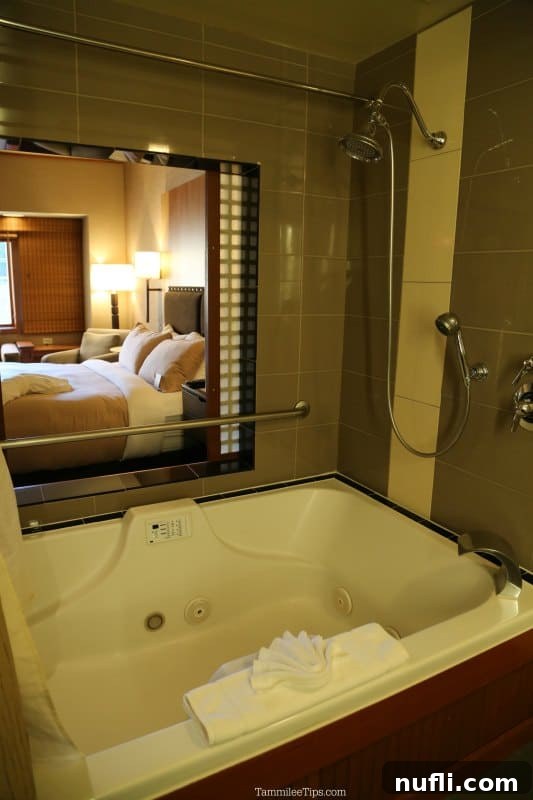 Jetted tub with towels looking through a window to the hotel bedroom 