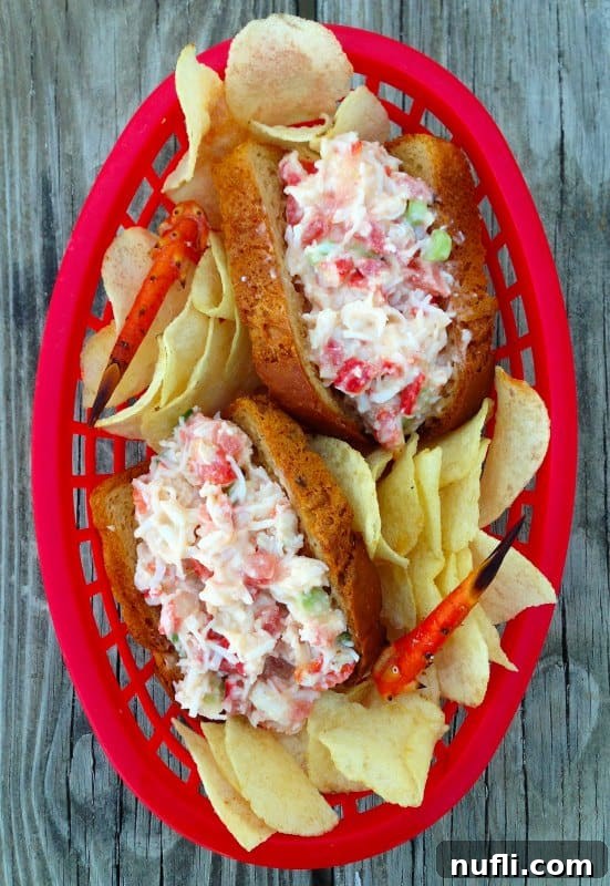 Two golden brown crab rolls served alongside a generous portion of crispy potato chips on a rustic wooden picnic table, highlighting a perfect summer meal.