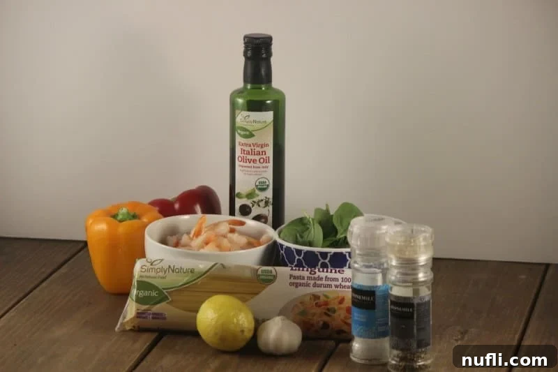 Speedy Garlic Shrimp Linguini 3 Fresh ingredients laid out on a wooden board: colorful bell peppers, raw shrimp, basil leaves, lemon, garlic cloves, salt and pepper shakers, olive oil, and linguini pasta