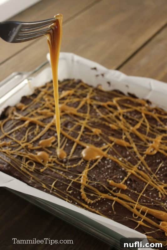 fork with caramel dripping off of it onto chocolate covered rice krispie treats