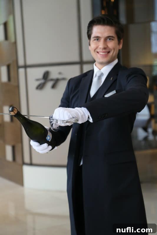 St. Regis Bangkok's Exquisite Afternoon Tea 2 A gentleman in a suit elegantly sabering a bottle of champagne, a St. Regis tradition.