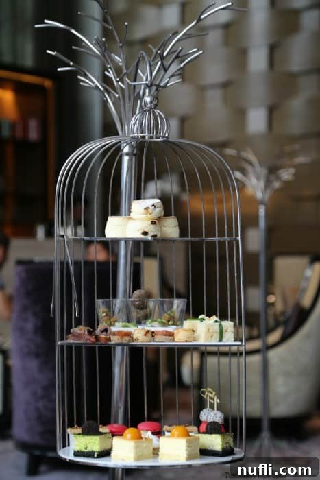 St. Regis Bangkok's Exquisite Afternoon Tea 3 A wire bird cage elegantly displays an assortment of tea sandwiches, exquisite desserts, and freshly baked scones.