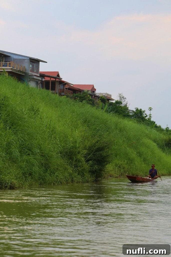 Thai fisherman in his small boat navigating the calm river waters