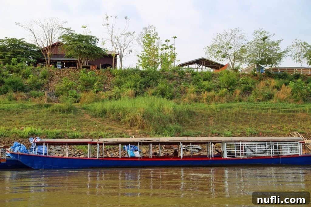 Mighty Mekong Voyage: Thailand to Laos 14 Several traditional Mekong River longtail boats pulled up and docked along a sandy bank, waiting for passengers or resting after a journey.