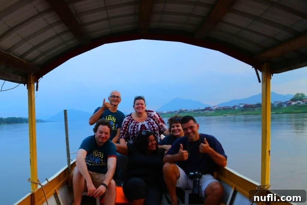 Mighty Mekong Voyage: Thailand to Laos 17 A group of smiling travelers enjoying a scenic boat ride on the Mekong River, capturing a memorable moment against the beautiful backdrop of the river and surrounding landscapes.