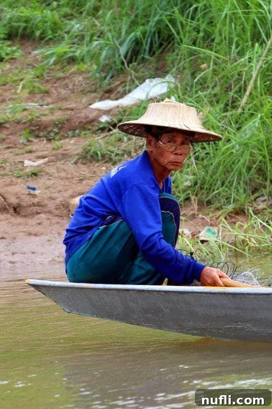 A Thai fisherman expertly casting his net on the Mekong River