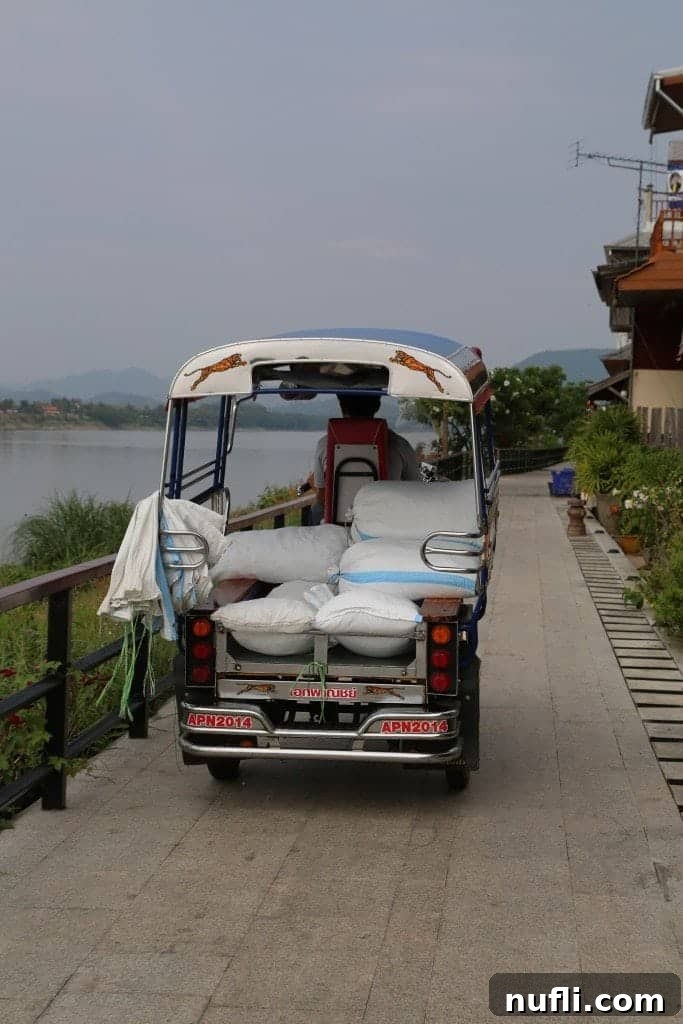 A traditional Thai tuk-tuk gracefully navigating the scenic route along the Mekong River in Chiang Khan.