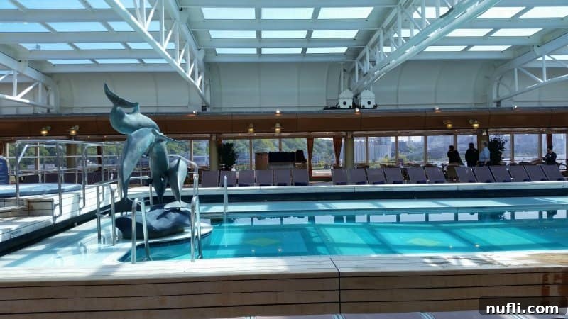 The inviting Lido Deck pool on the Westerdam, featuring a dolphin sculpture and a retractable roof, ideal for any climate, especially for Alaska cruises.