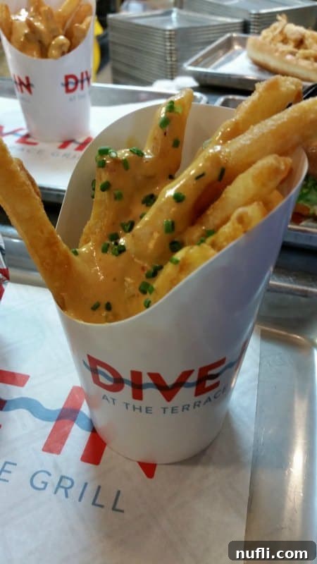 Close-up of crispy fries generously covered in rich, creamy cheese sauce, a popular and indulgent side dish at Dive In.
