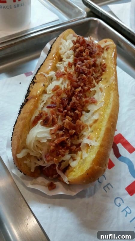Gourmet hot dog topped with crispy bacon bits and tangy sauerkraut for a flavorful bite