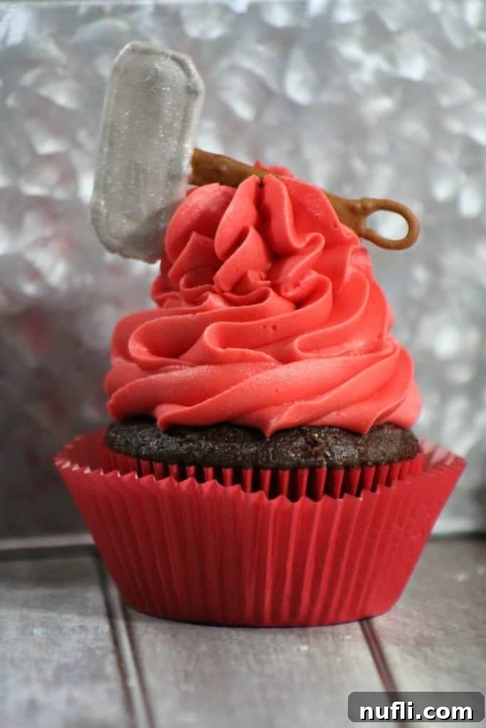 Close-up of a perfectly frosted red Marvel Thor Cupcake, adorned with a replica of Thor's hammer Mjolnir.
