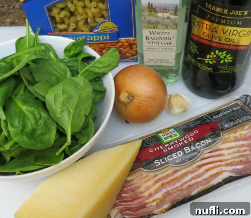 Spinach, onion, bacon, cheese, pasta, olive oil and balsamic vinegar on the counter