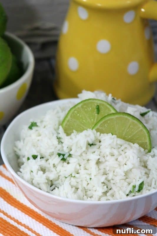 Cilantro Lime Rice in a white bowl with lime wedges next to a yellow pitcher