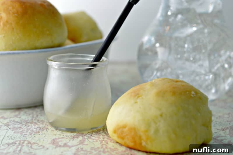 Butter in a glass jar with a knife next to rolls, ready to be served.