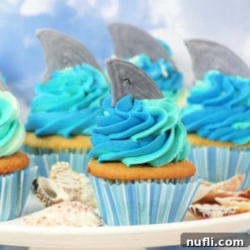 Close-up of freshly frosted shark cupcakes on a platter, ready to be served at an ocean-themed party.