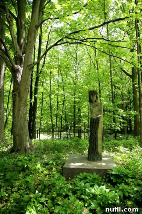 Meijer Gardens Grand Rapids Art and Nature Escape 7 Abstract stone sculpture, 'Stele Garuge,' nestled among trees and foliage in a woodland setting.