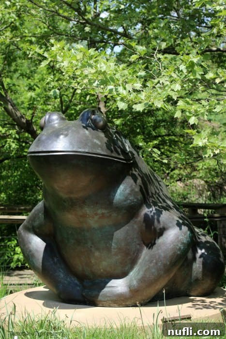 Meijer Gardens Grand Rapids Art and Nature Escape 8 Large, friendly frog sculpture surrounded by green plants and trees in a garden setting.