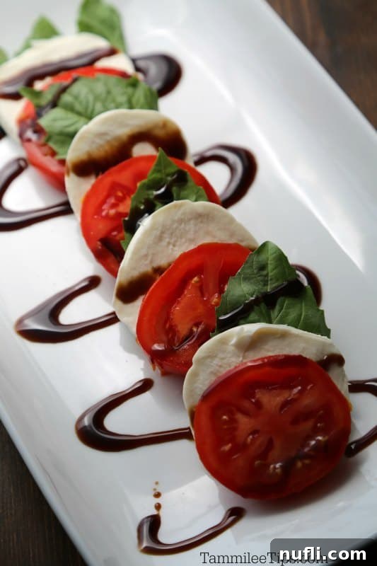 Simple & Irresistible Caprese Salad 3 Tomato slices, mozzarella, basil leaves on a platter with balsamic glaze.