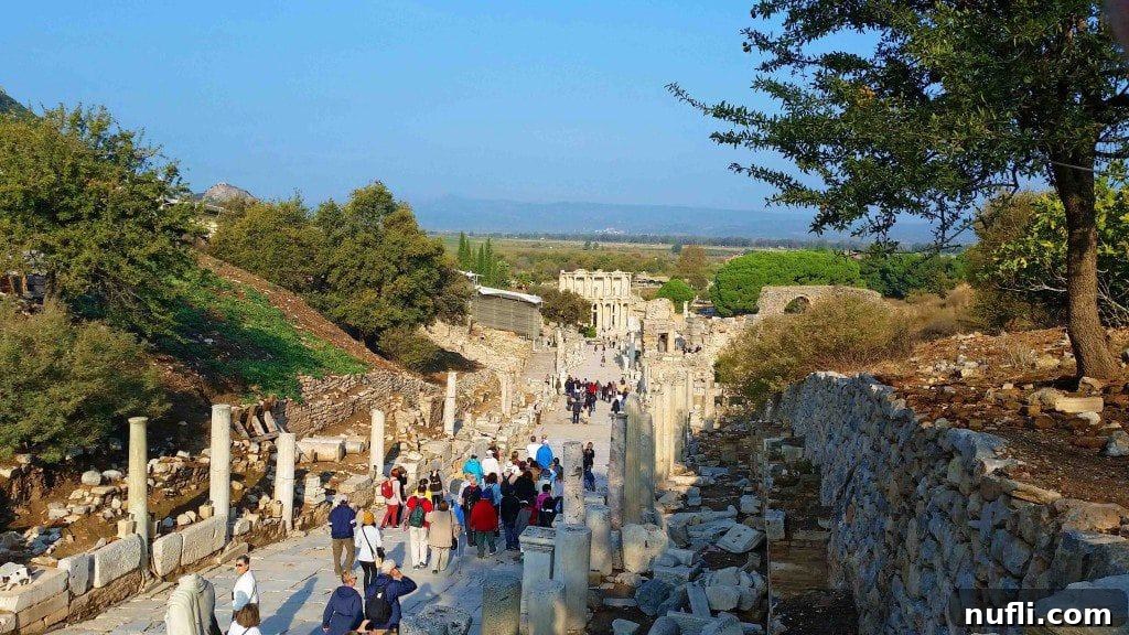 Visitors descending into the ancient city of Ephesus, surrounded by monumental ruins.