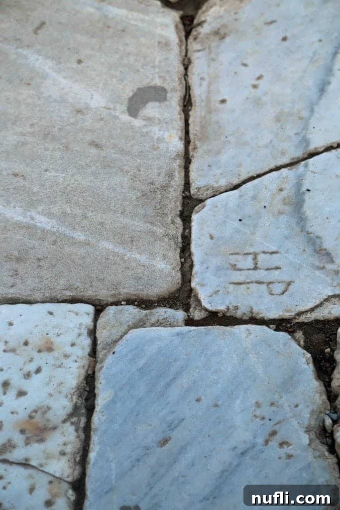 Close-up of ancient initials carved into the stone pathway at Ephesus, indicating the craftsmanship of workers.