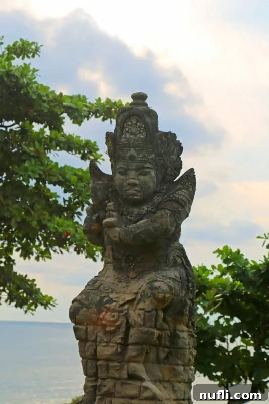 Balinese stone statue with intricate carvings against the backdrop of the ocean at Tanah Lot