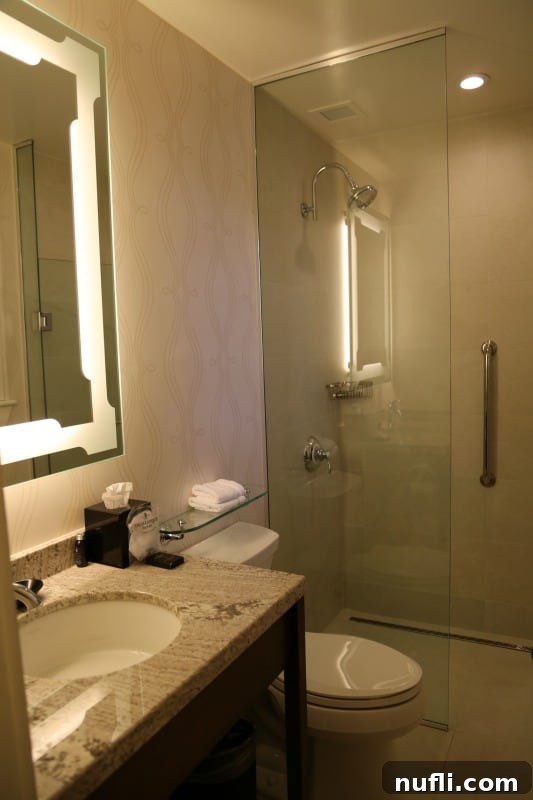 A modern and spacious hotel bathroom at The Algonquin Resort, featuring a walk-in shower with glass doors and elegant tiling.