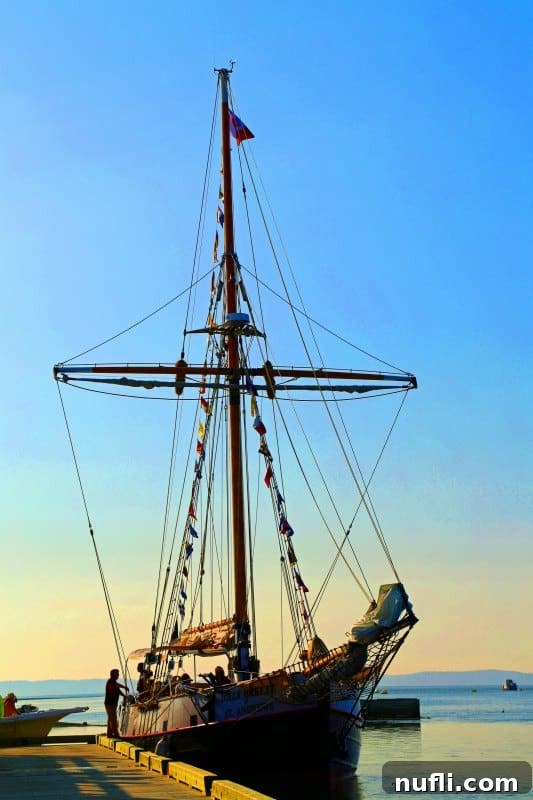 A tall ship with colorful flags docked in the picturesque port of St. Andrews by-the-Sea