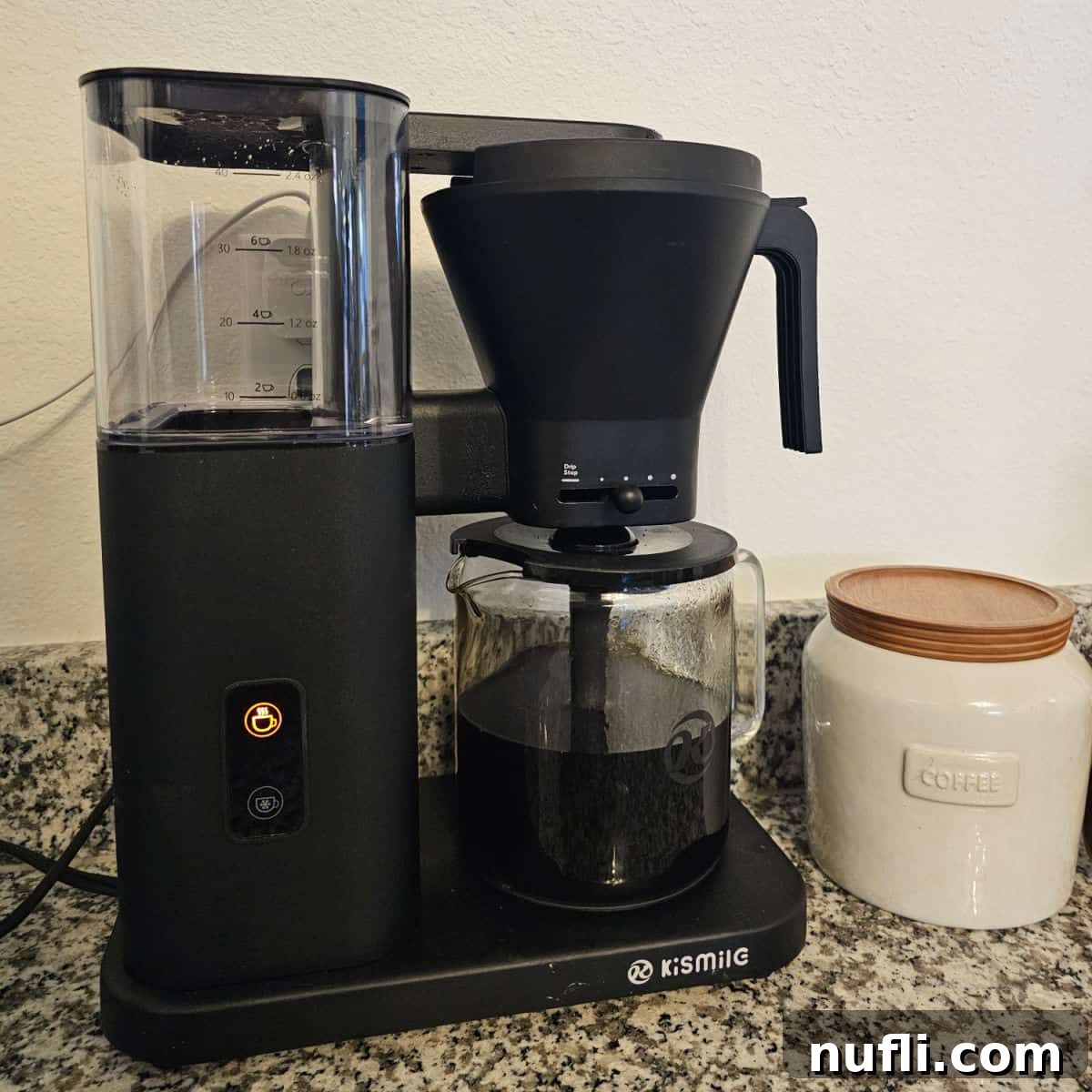 Kismile Coffee maker brewing next to a container with coffee on it